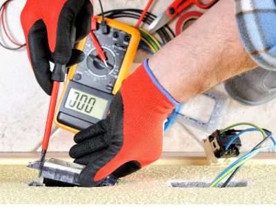 Electrician working on outlet, Airco Service logo in bottom right